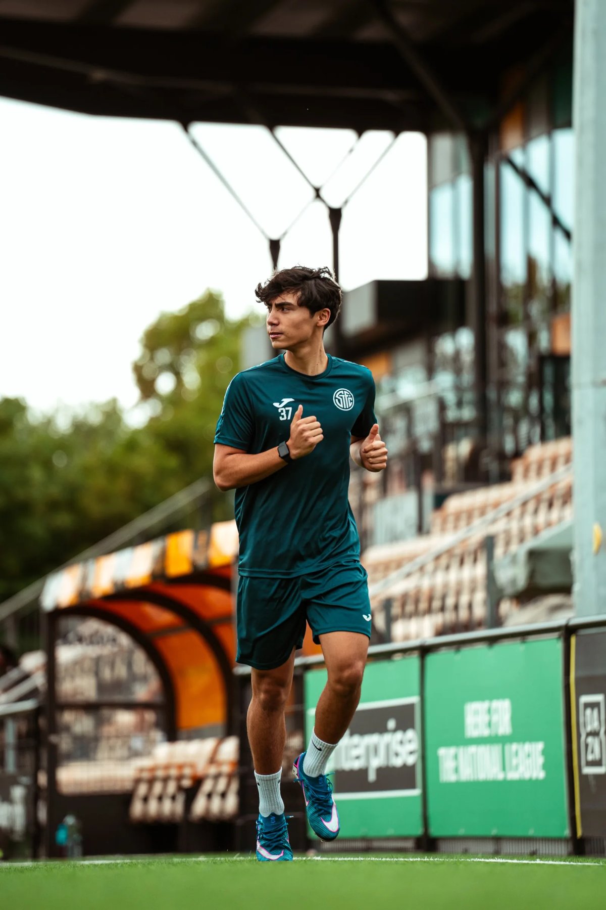 A player running past the main stand at Arbour Park